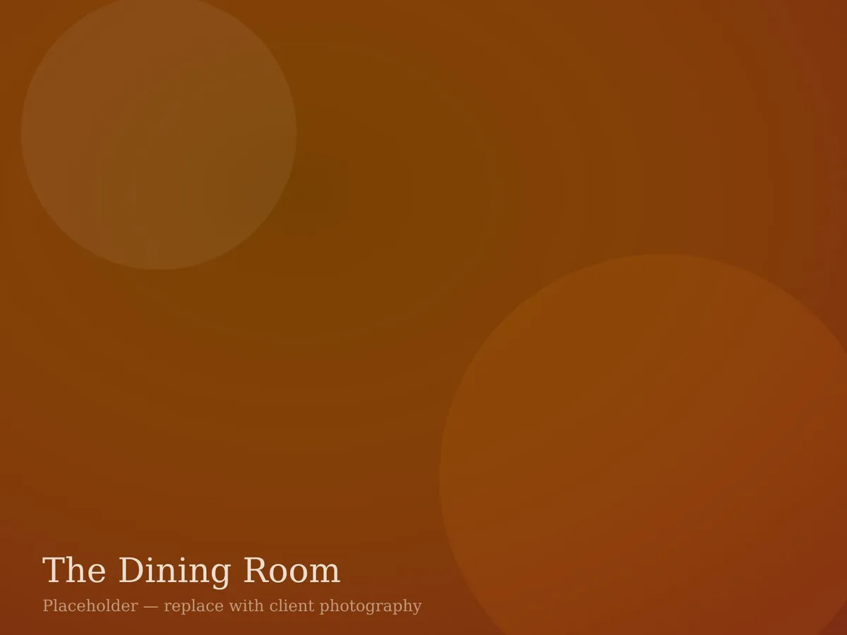 The Juniper Table dining room with warm wood tables, leather banquettes, and evening lighting